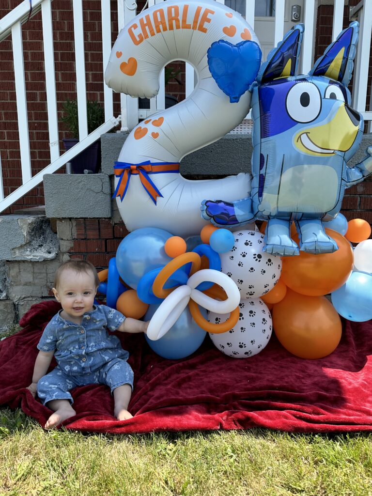 a birthday balloon set with a large 2 that says Charlie next to a giant Bluey and some fun balloon base