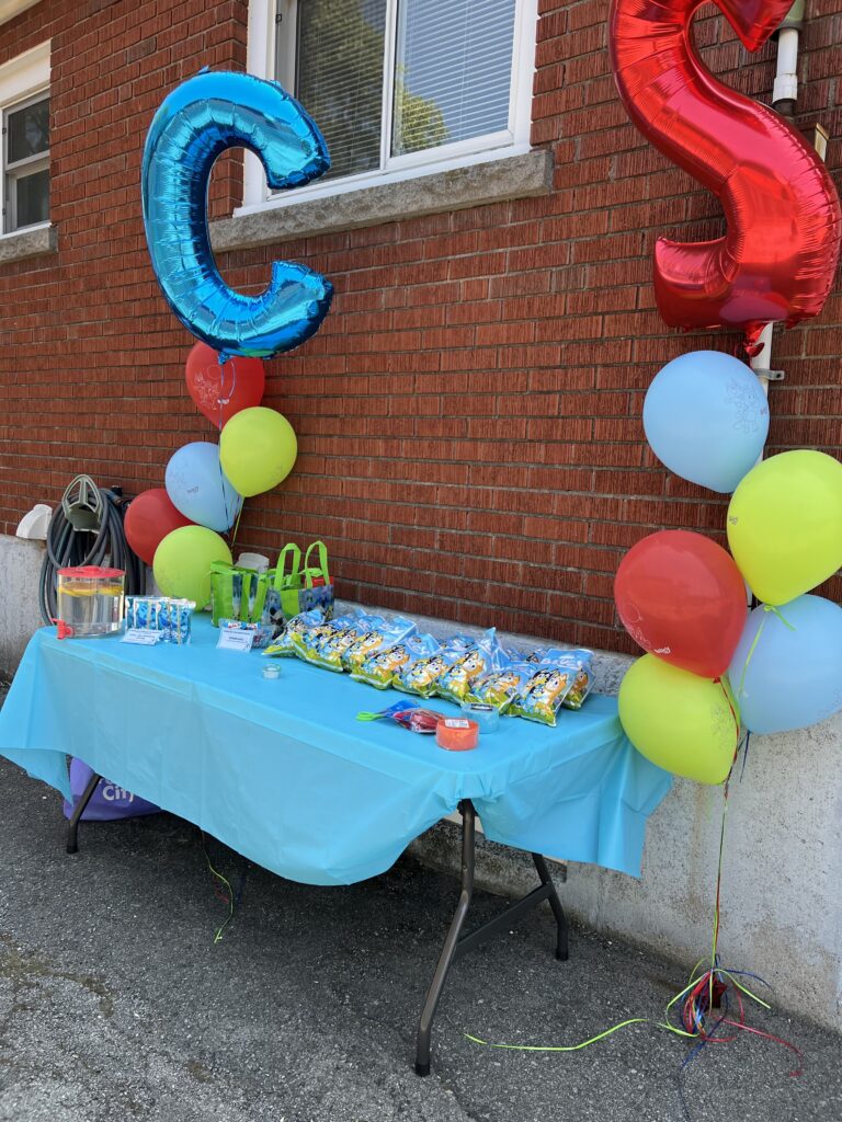 Birthday balloons around a table of loot bags and drinks